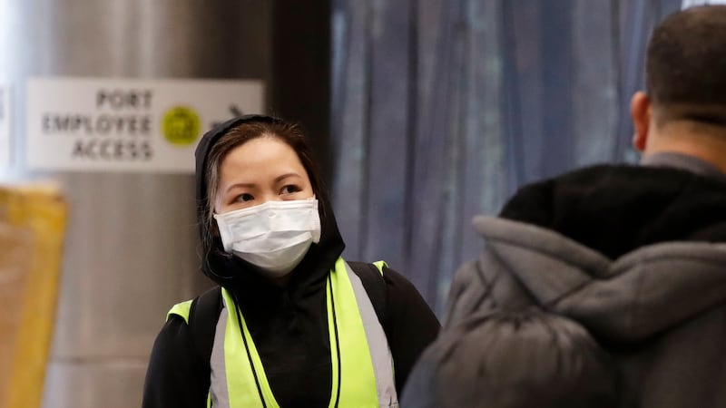 A airport agent, who declined to be identified, wears a protective mask as she waits to assist...