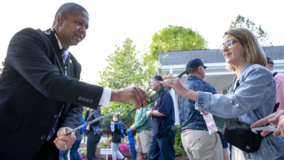 Patrons get eclipse glasses as they enter the gates at Augusta National Golf Club on April 8,...